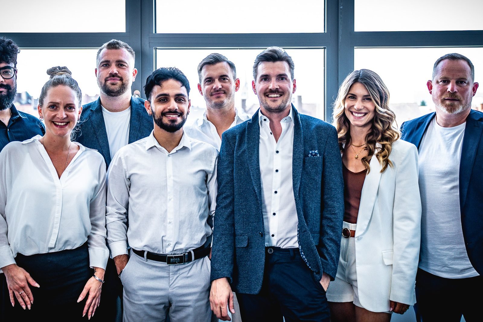 Das Team der Finanzmacher, gemeinsam vor einer Fensterfront